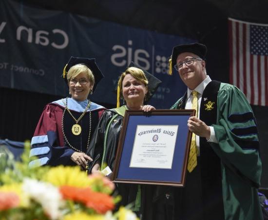 Professor of Occupational Therapy Mary Siniscaro stands between Provost Todd Pfannestiel and President Laura Casamento, holding her award at the 2023 Undergraduate Commencement Ceremony.