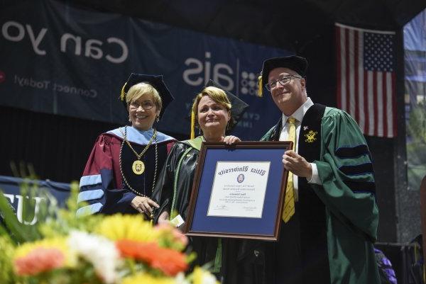 职业治疗教授Mary Siniscaro站在教务长Todd Pfannestiel和校长Laura casmento之间, 在2023年本科毕业典礼上颁奖.