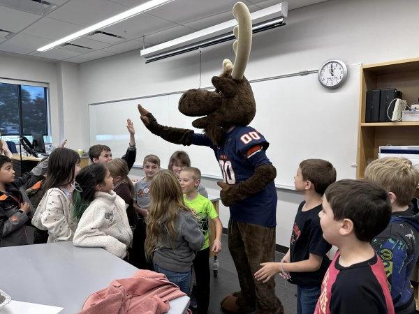 Trax the Moose high fives with elementary students from Little Falls.