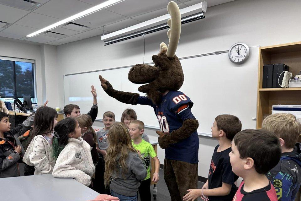 Trax the Moose high fives with elementary students from Little Falls.